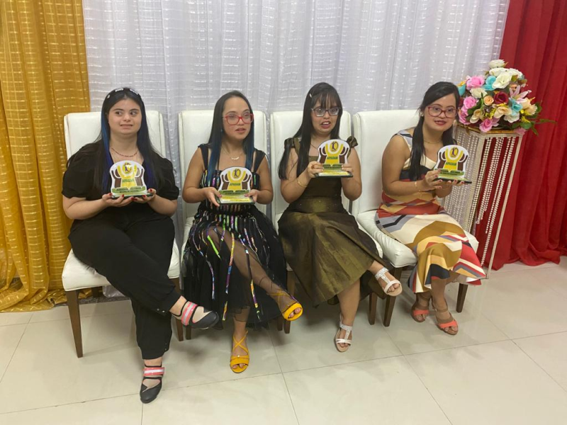 Quatro moças Down segurando prêmio em suas mãos